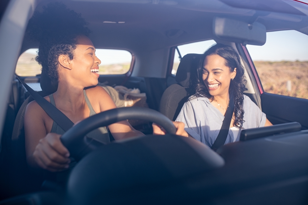 Two women driving on a roadtrip during the summer